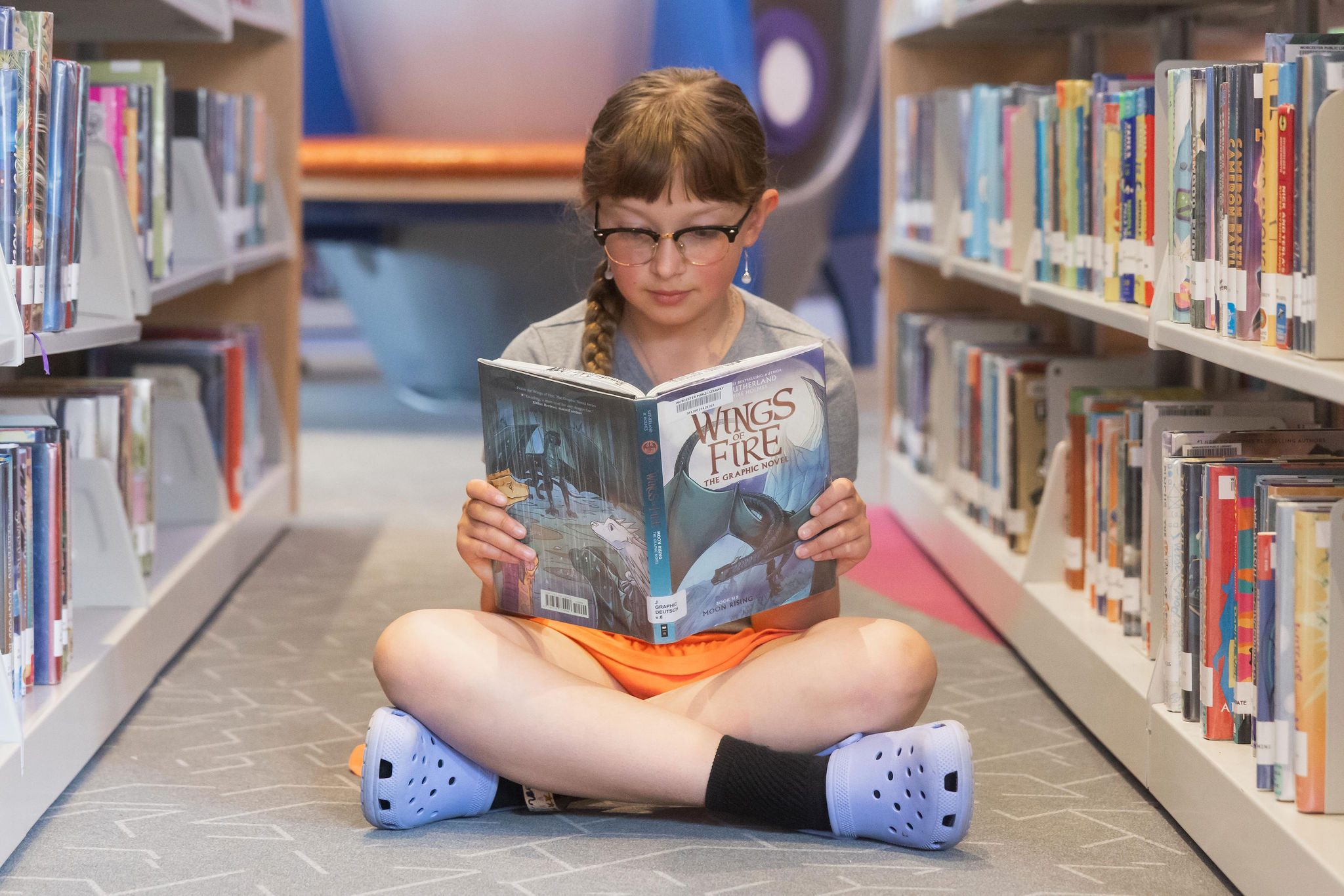 A child sits in the stacks reading a book.
