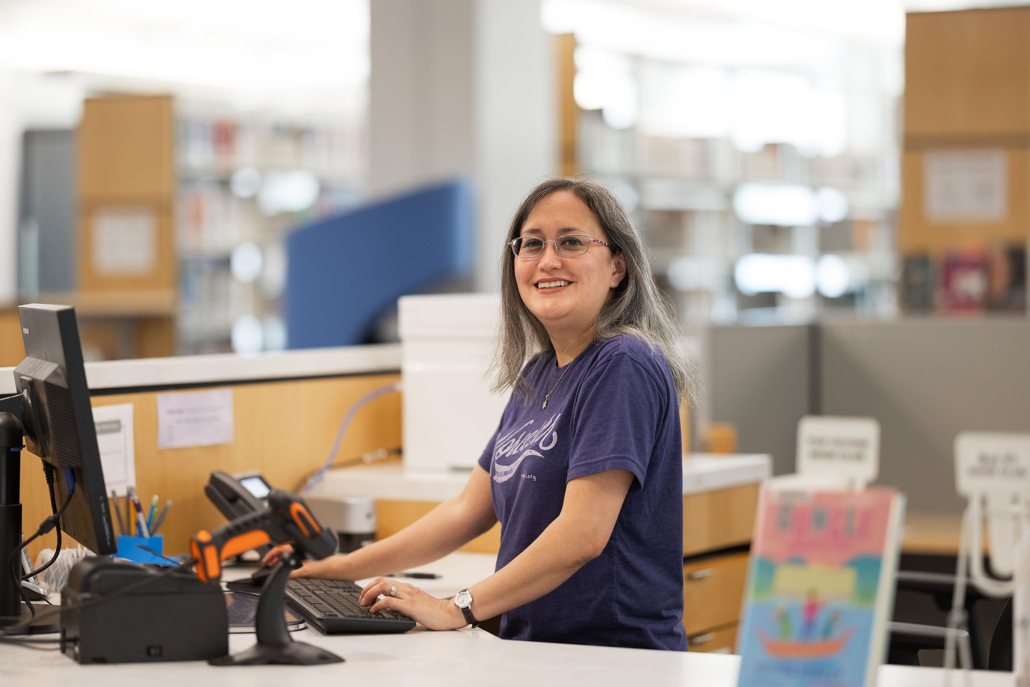 A librarian at an information desk waits to help patrons.