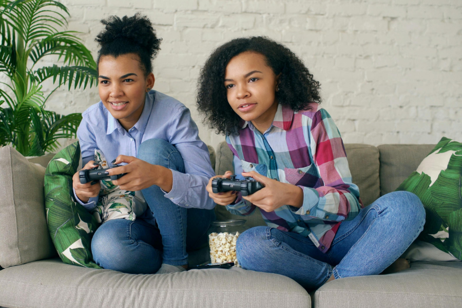 Two young people playing video games, points to place a hold on gaming at the Main Library.
