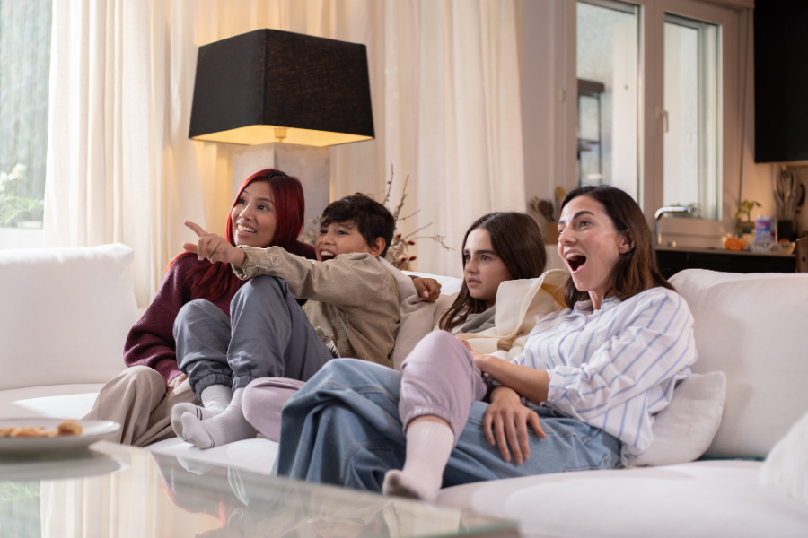 A group sits on a couch watching a show, points to Kanopy.