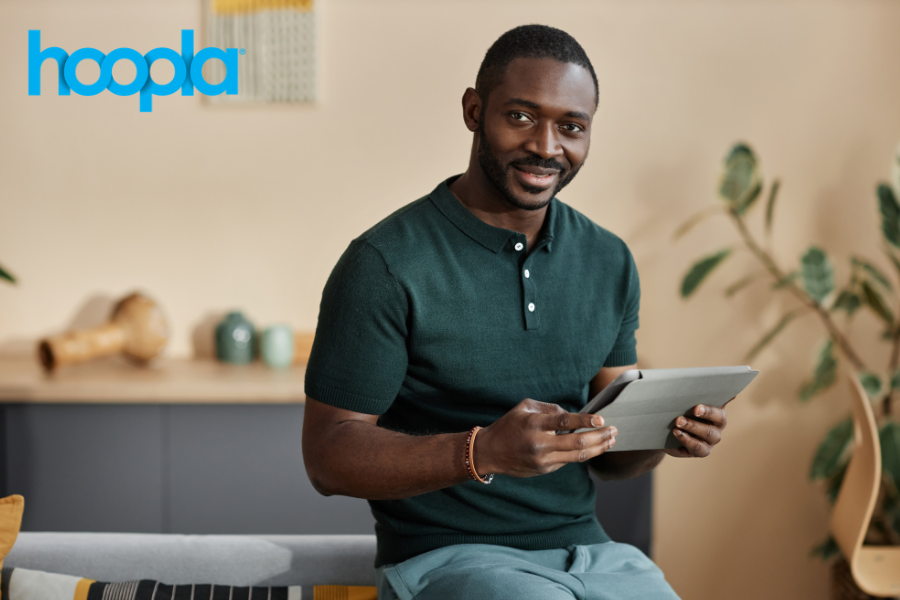 Person watching something on a tablet, points to Hoopla site.
