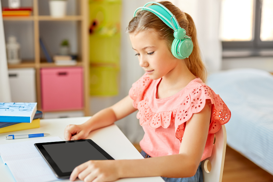 Girl with headphones watches something on tablet.