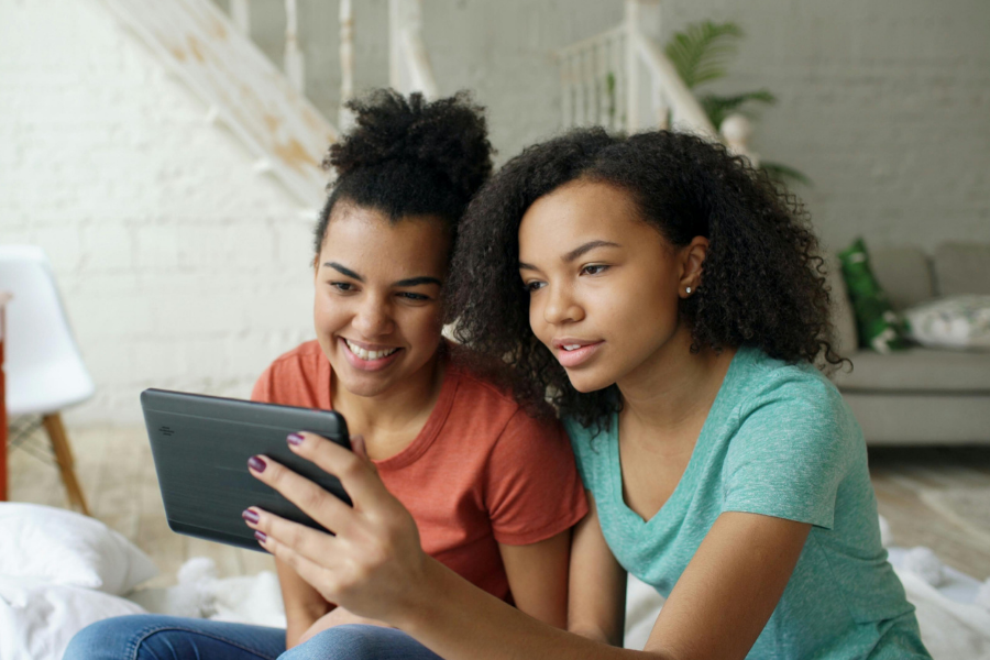 Two teens reading together on a tablet.