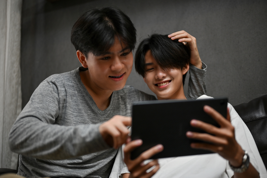 Two teens watch something on a tablet.