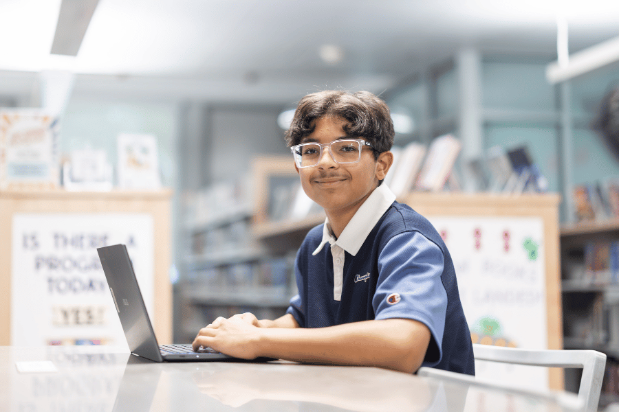 Teen in Teen Space works on a Chromebook.