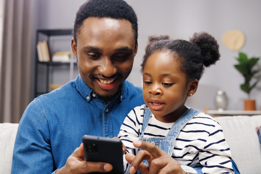 Dad and kid reading on cell phone.