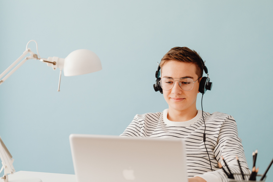 A kid with headphones on works on a laptop.
